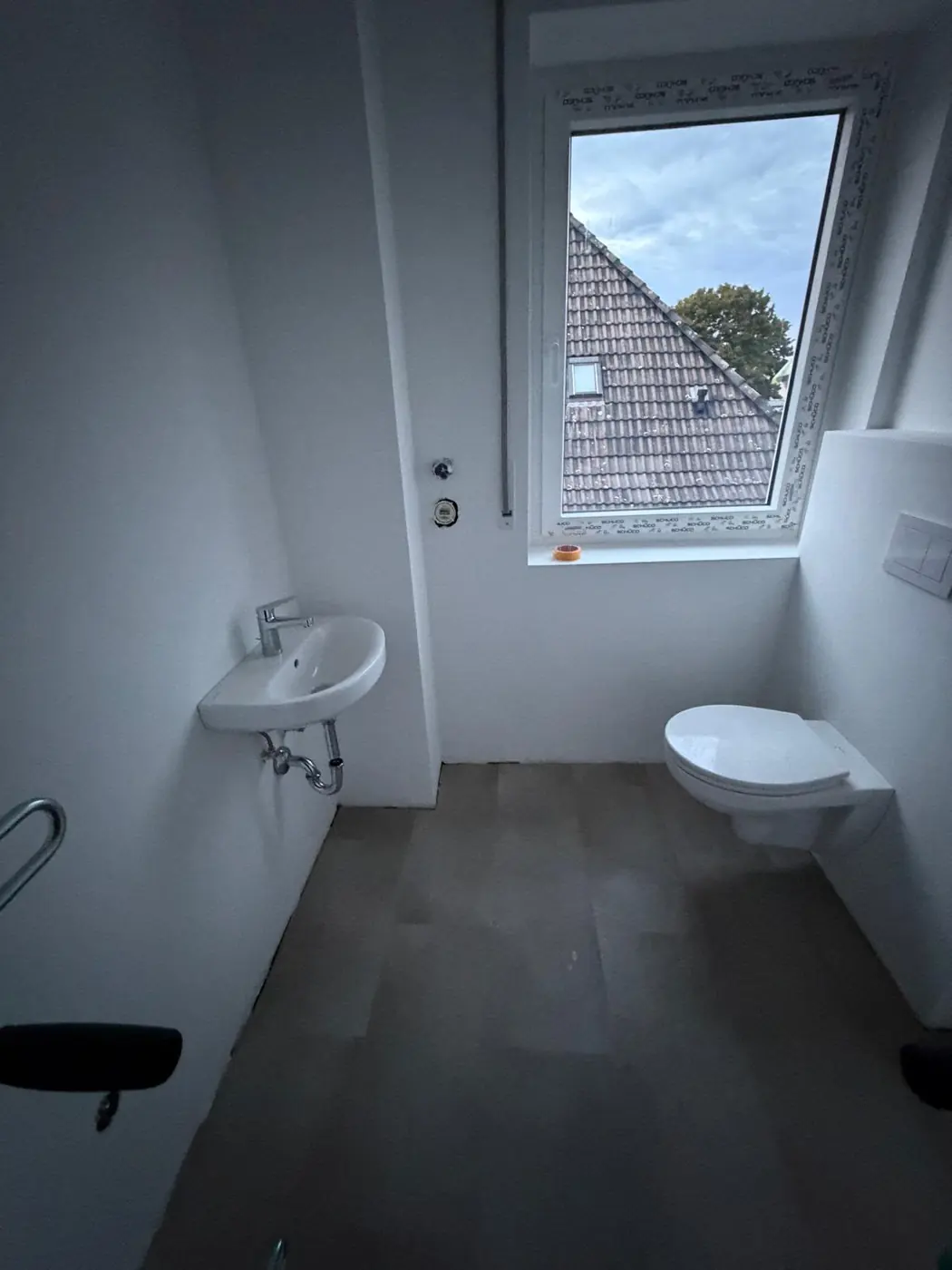Renoviertes Badezimmer mit Waschbecken, WC und grauem Boden