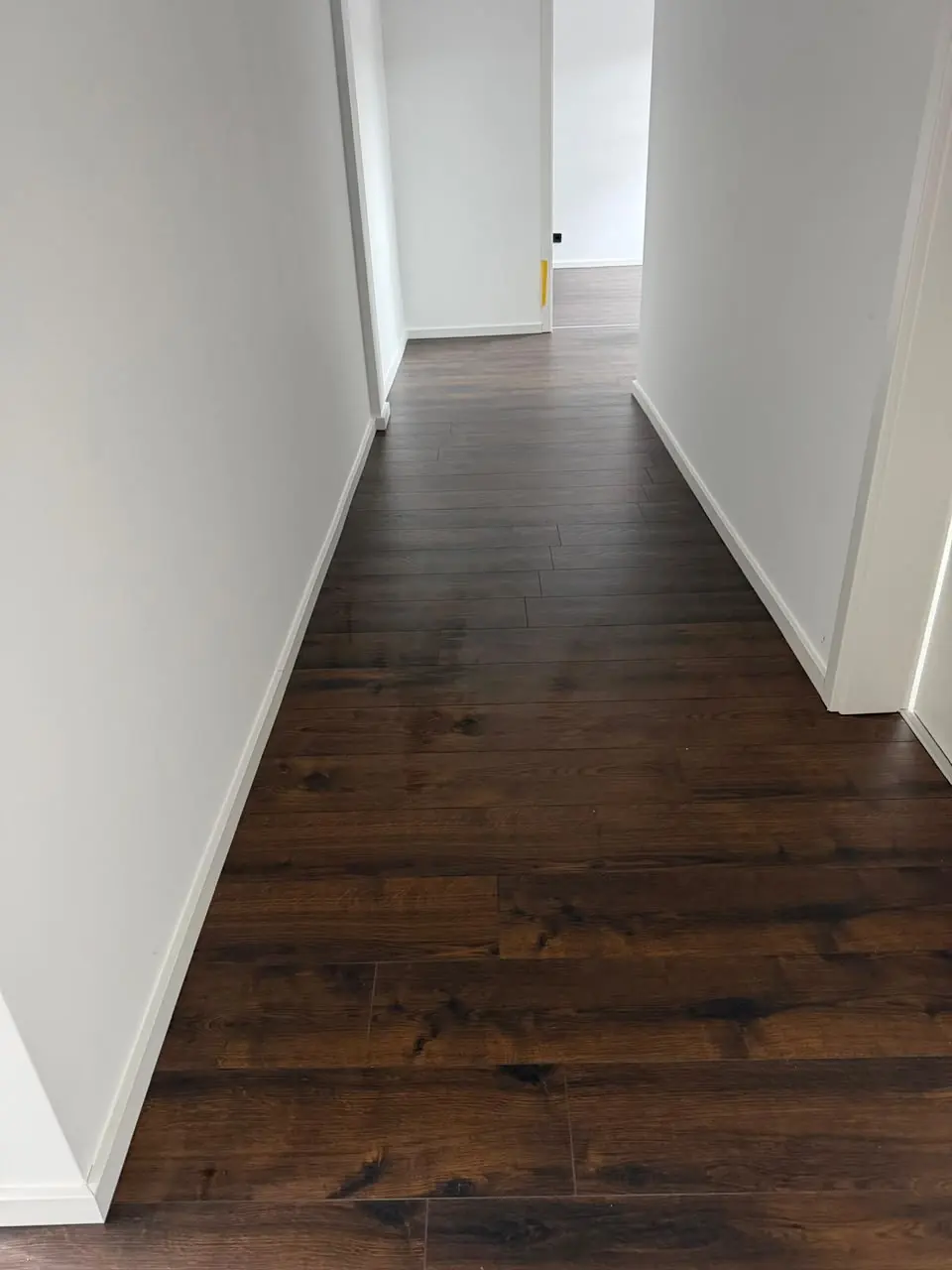 Langer Flur mit dunklem Boden in Holzoptik