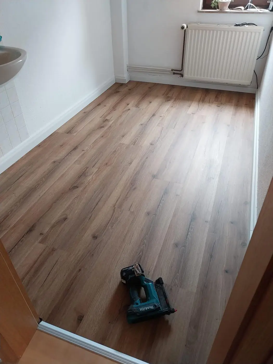 Zimmer mit neu verlegtem Boden in Holzoptik unter dem Fenster