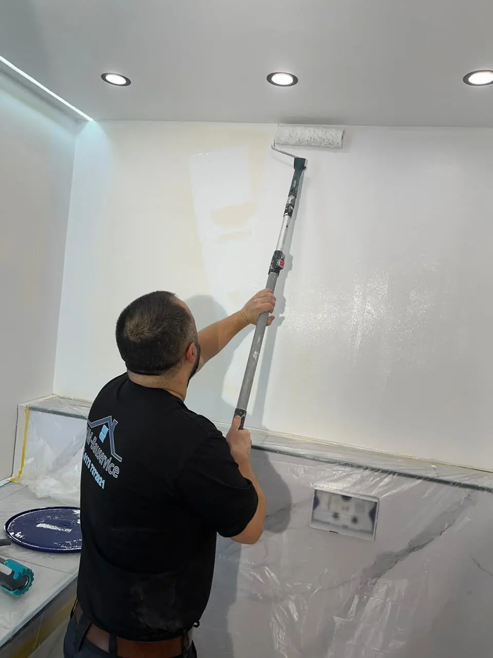 Handwerker bearbeitet eine Wand in einem Raum mit Deckenbeleuchtung