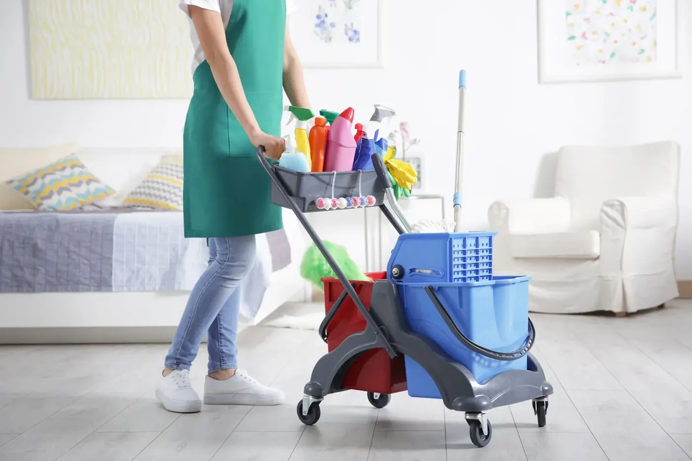 Reinigungskraft mit Reinigungswagen in einem hellen Wohnraum
