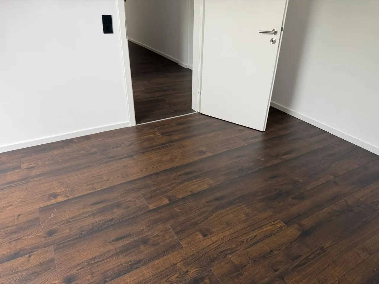 Heller Raum mit neu verlegtem dunklem Boden in Holzoptik